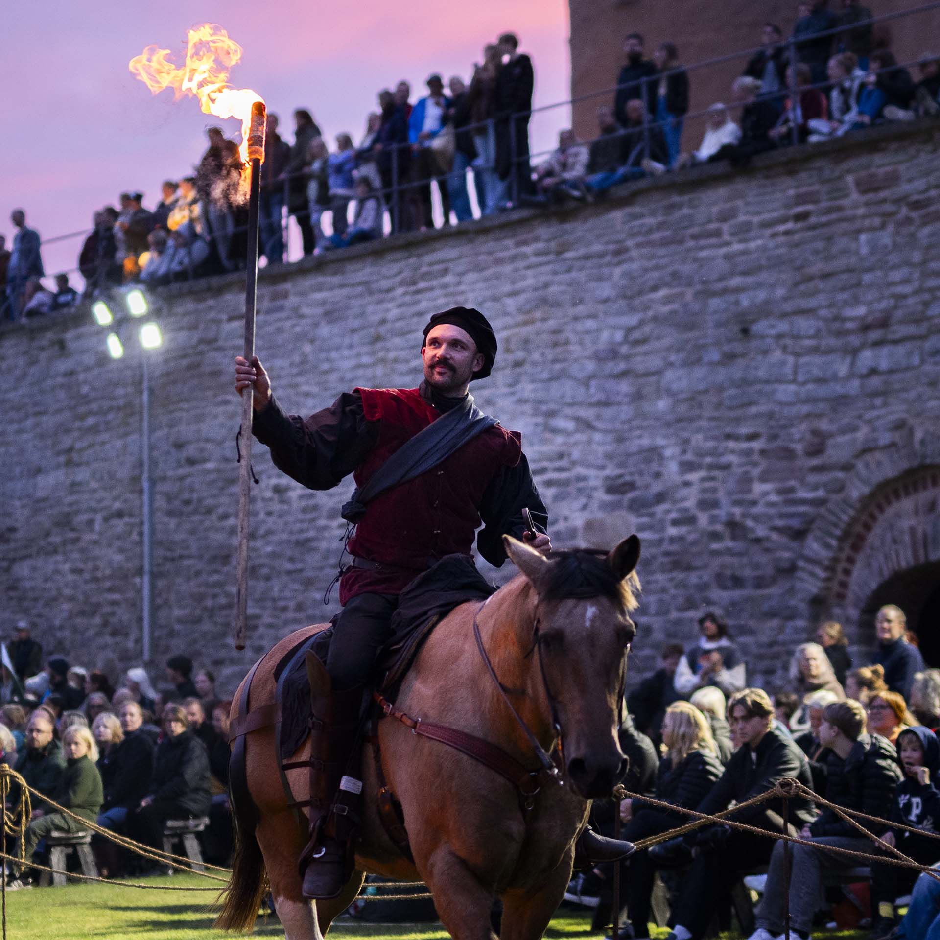 Riddare med facklor i händerna rider på hästar vid Kalmar Slott.