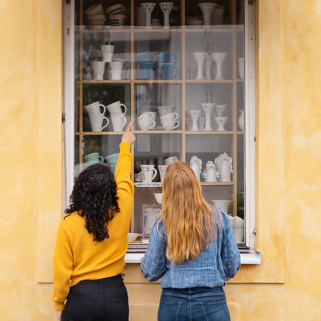 Olida och Helena tittar in i ett skyltfönster med keramik.