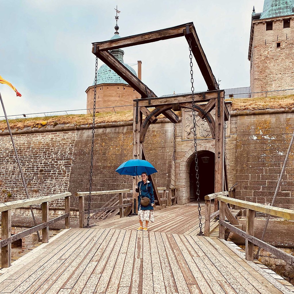 Marika Axén står på vindbryggan utanför Kalmar Slott och håller i ett paraply i handen.