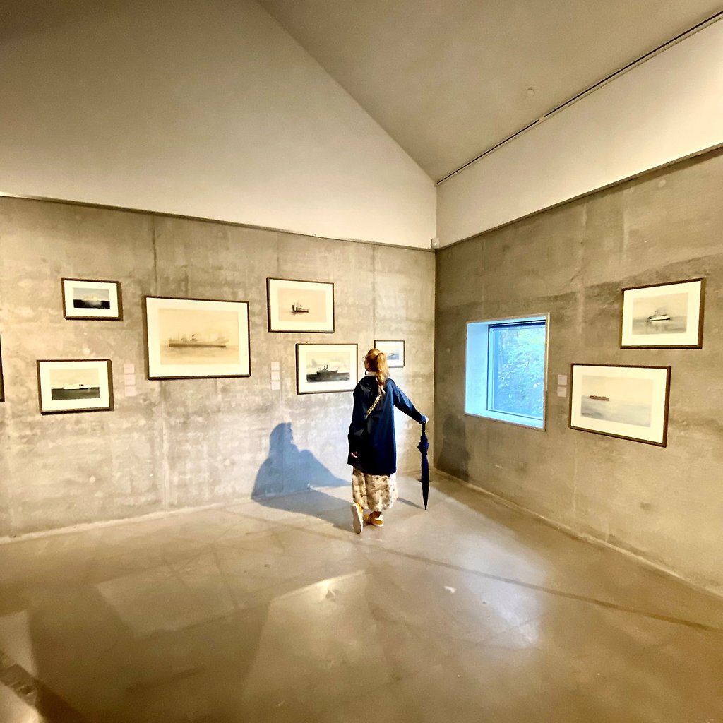 Marika Axén tittar på tavlor inne i en stor sal med betongväggar inne i konstmuseet.