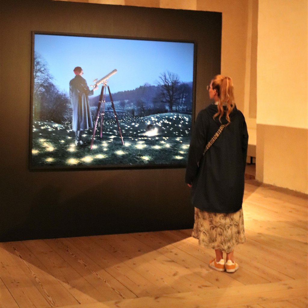 Marika Axén tittar på en stor tavla med Erik Johanssons fotokonst.