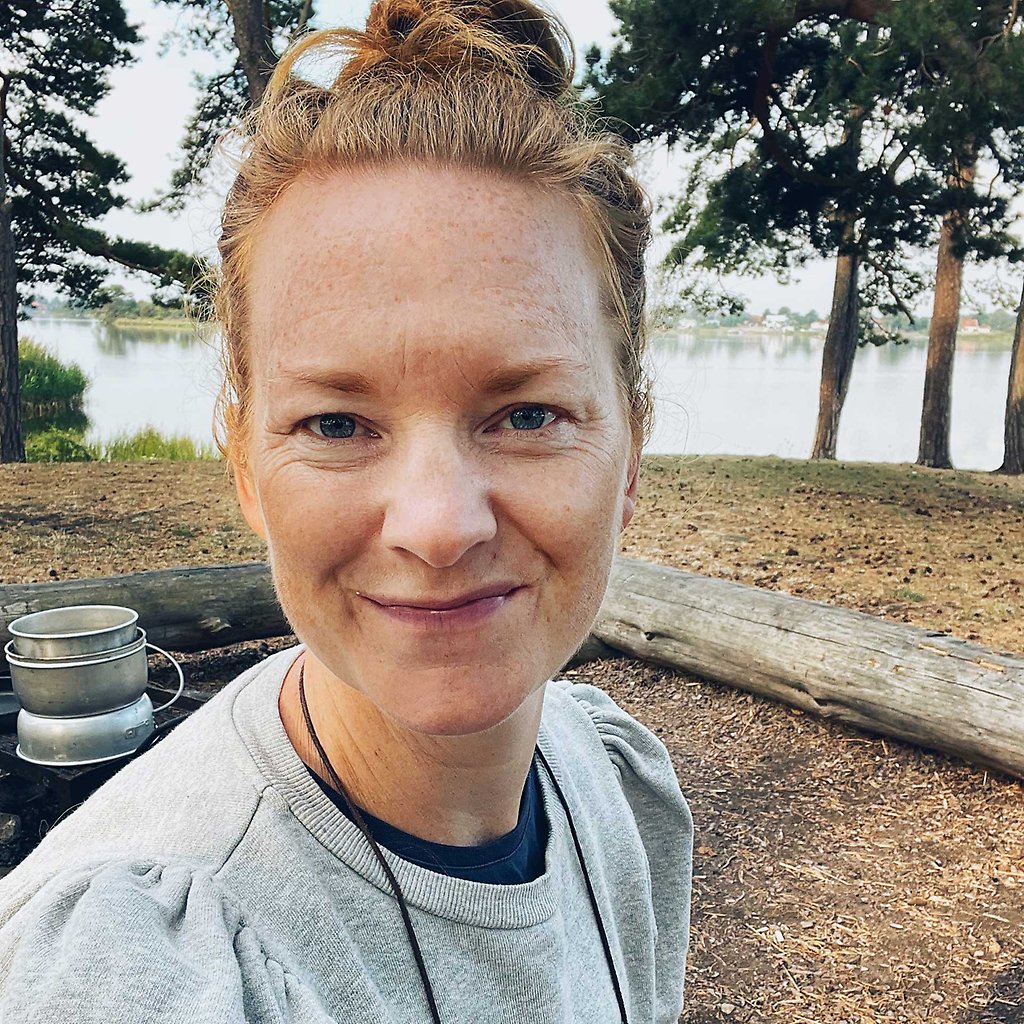 Sara Zetterströms ansikte utomhus med hav och träd som bakgrund.