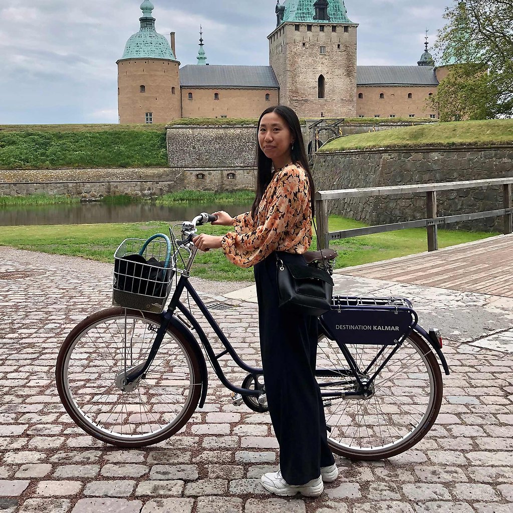 Thuha Nguyen står framför Kalmar Slott och håller i en cykel.