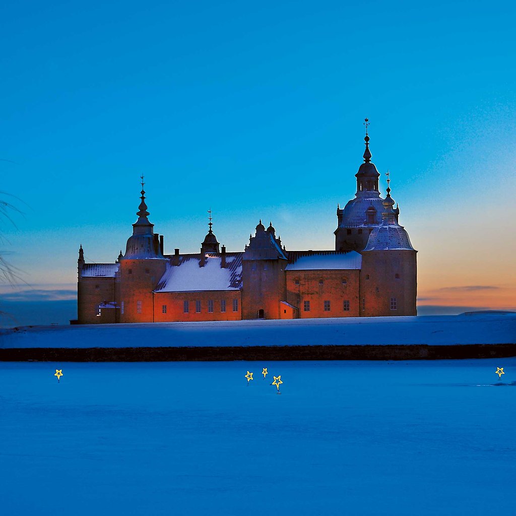 Kalmar Slott i snö med julbelysning på isen framför slottet.