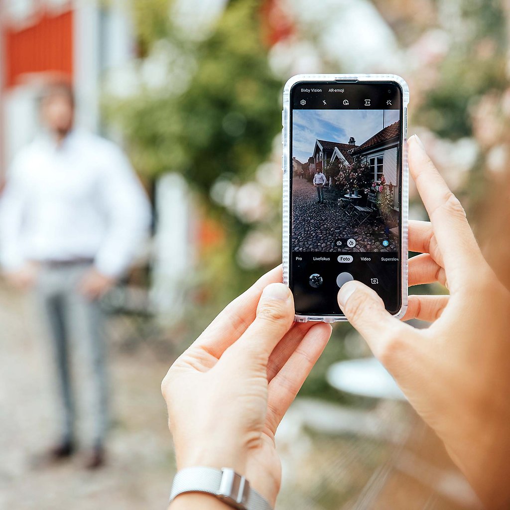 Kvinna fotar med sin mobilkamera på kullerstensgata i gamla stan. 