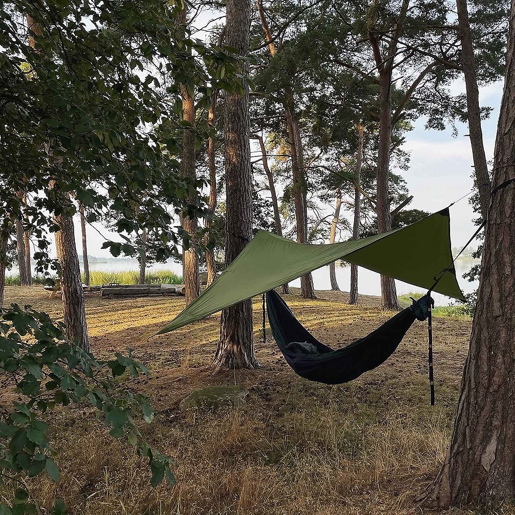 En hängmatta med ett vindskydd över hänger mellan ett par träd.