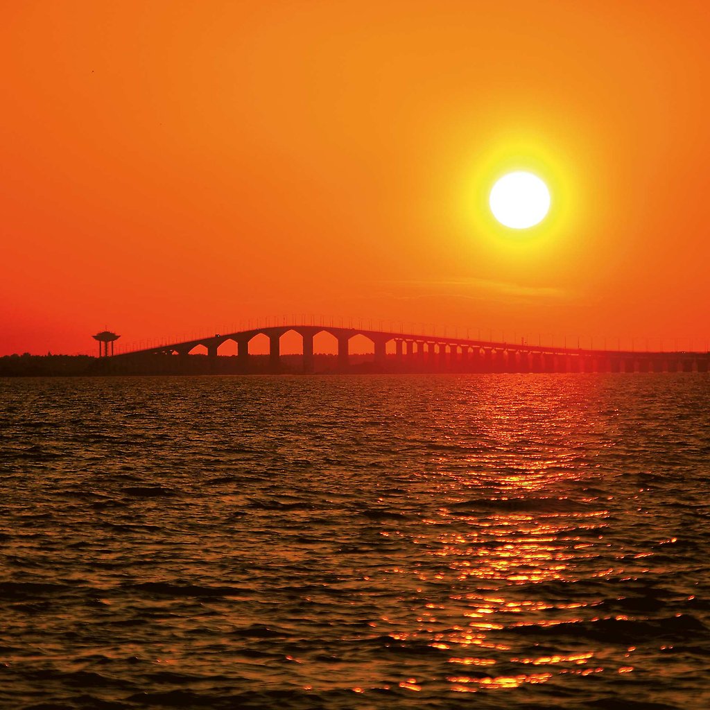Orange himmel med en sol som går upp över Ölandsbron