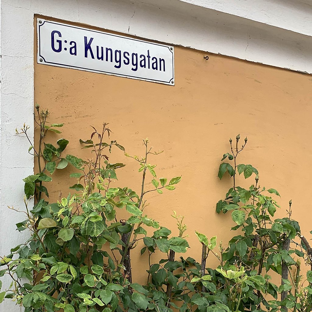 En gul husvägg med en gatuskylt med texten G:a Kungsgatan.