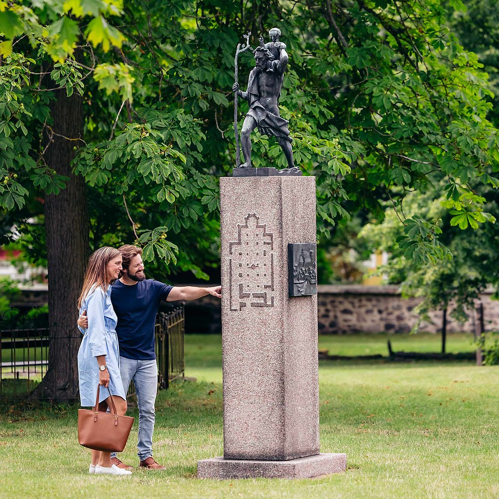 Par i Gamla kyrkogården som tittar på staty. 