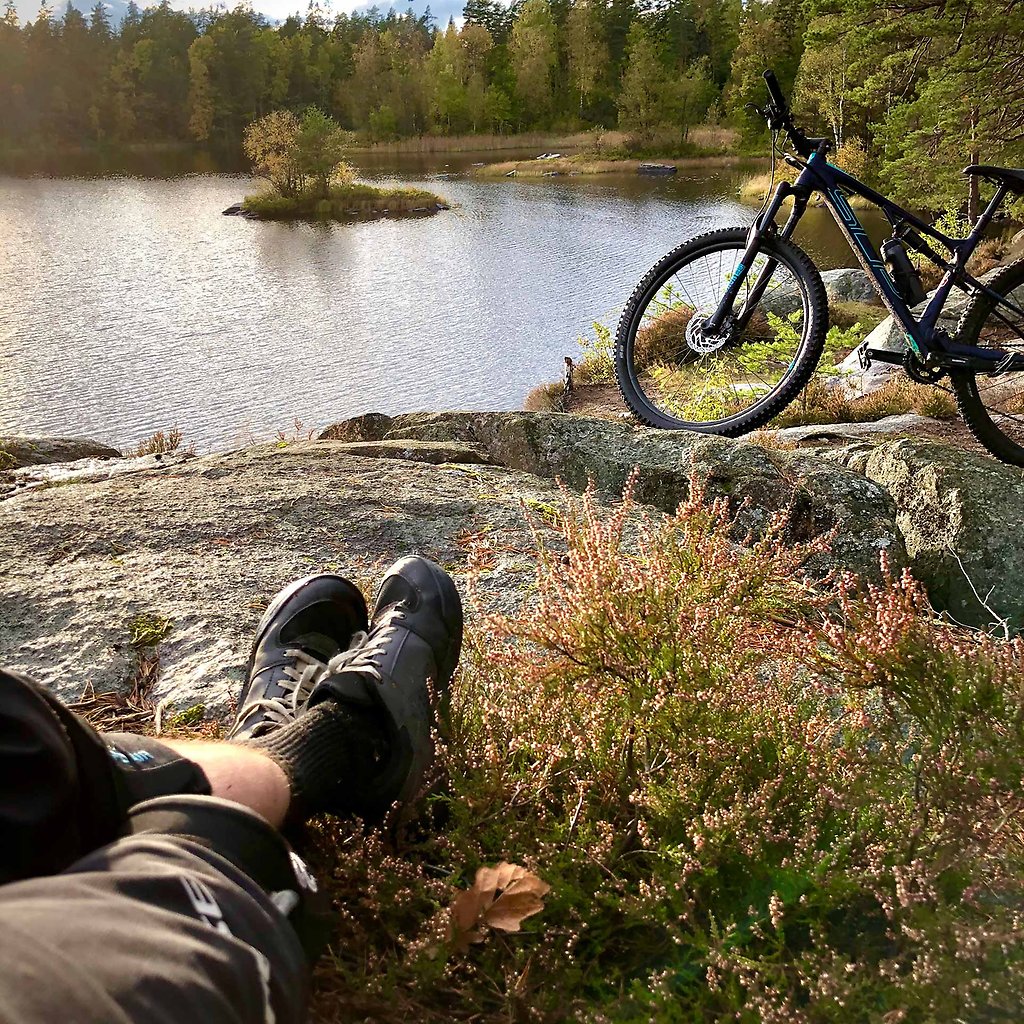 Two legs resting on the edge of a cliff. The ocean and a parked bicycle can be seen in the background.