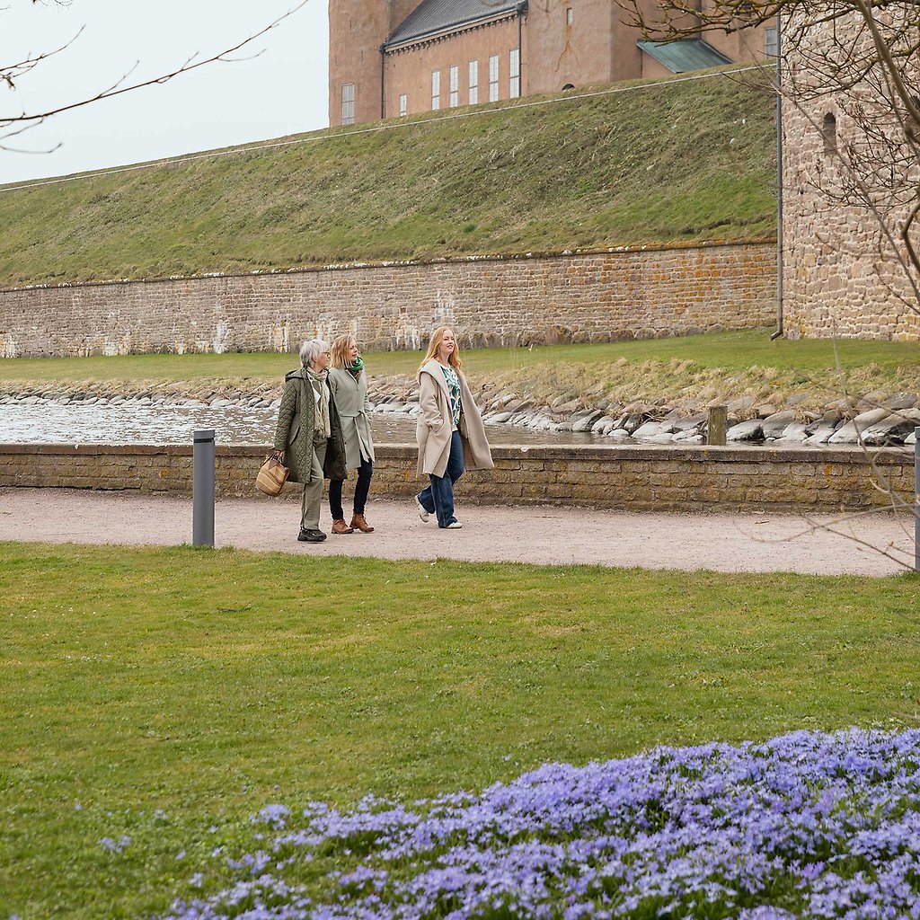 Helena, hennes mamma och syster promenerar framför Kalmar Slott. I förgrunden syns scilla som blommar.