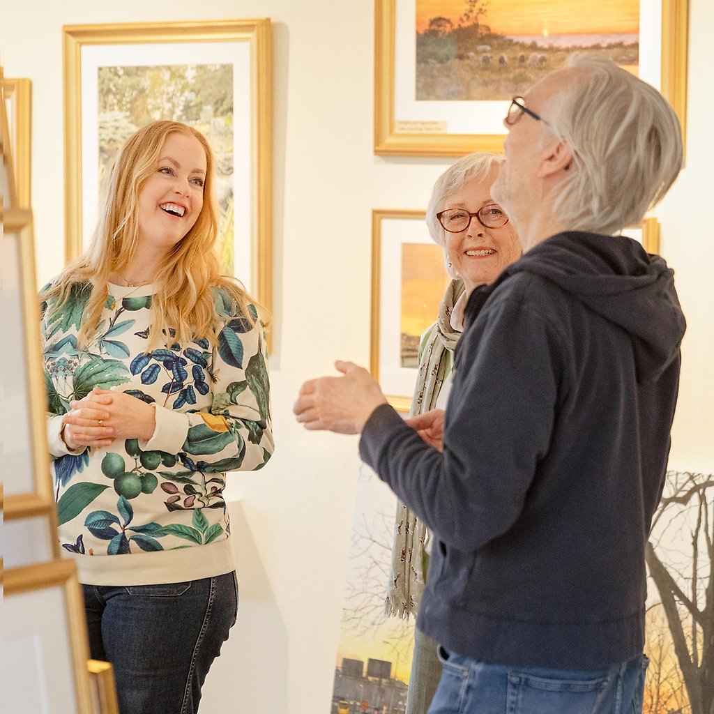 Helena, hennes mamma och konstnären Johan Persson står och pratar i ateljén omgivna av tavlor.