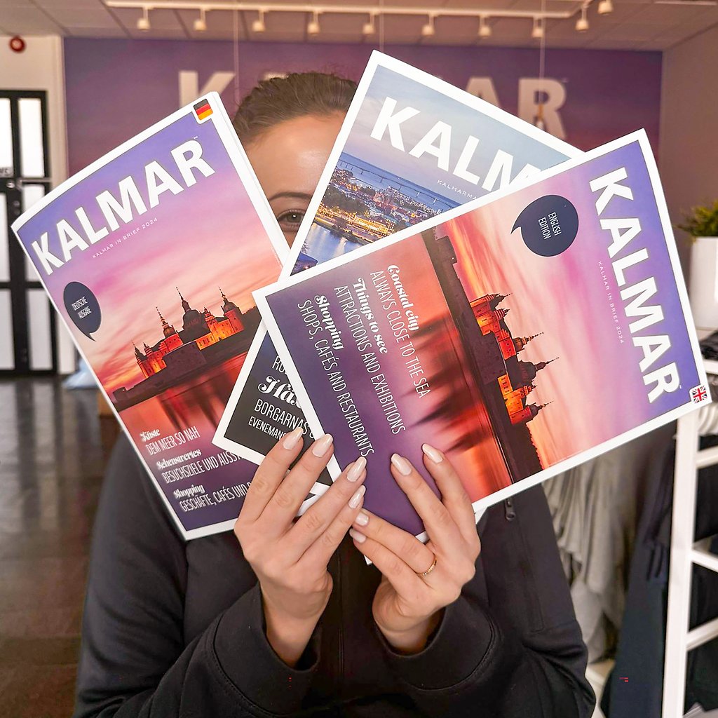 En person håller upp tre broschyrer
