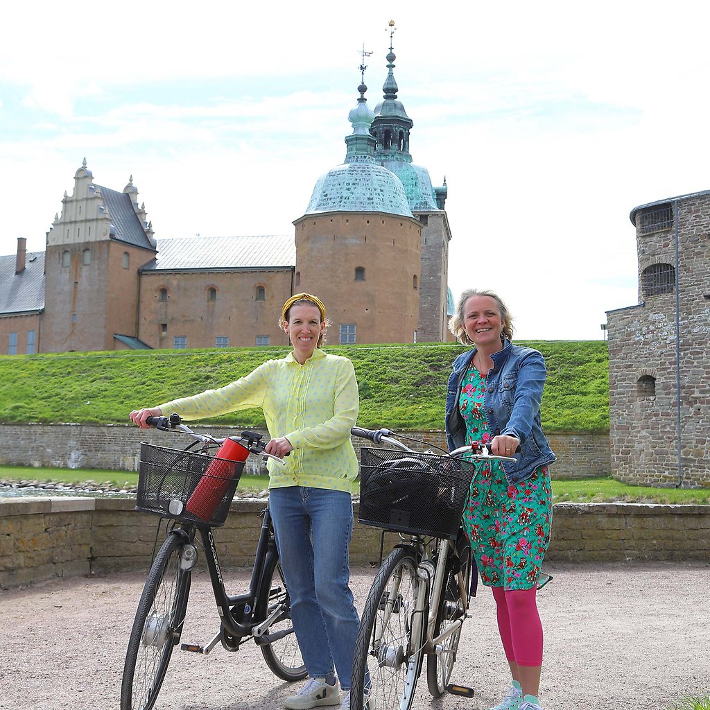 Stina och Elvira står med varsin cykel framför Kalmar Slott