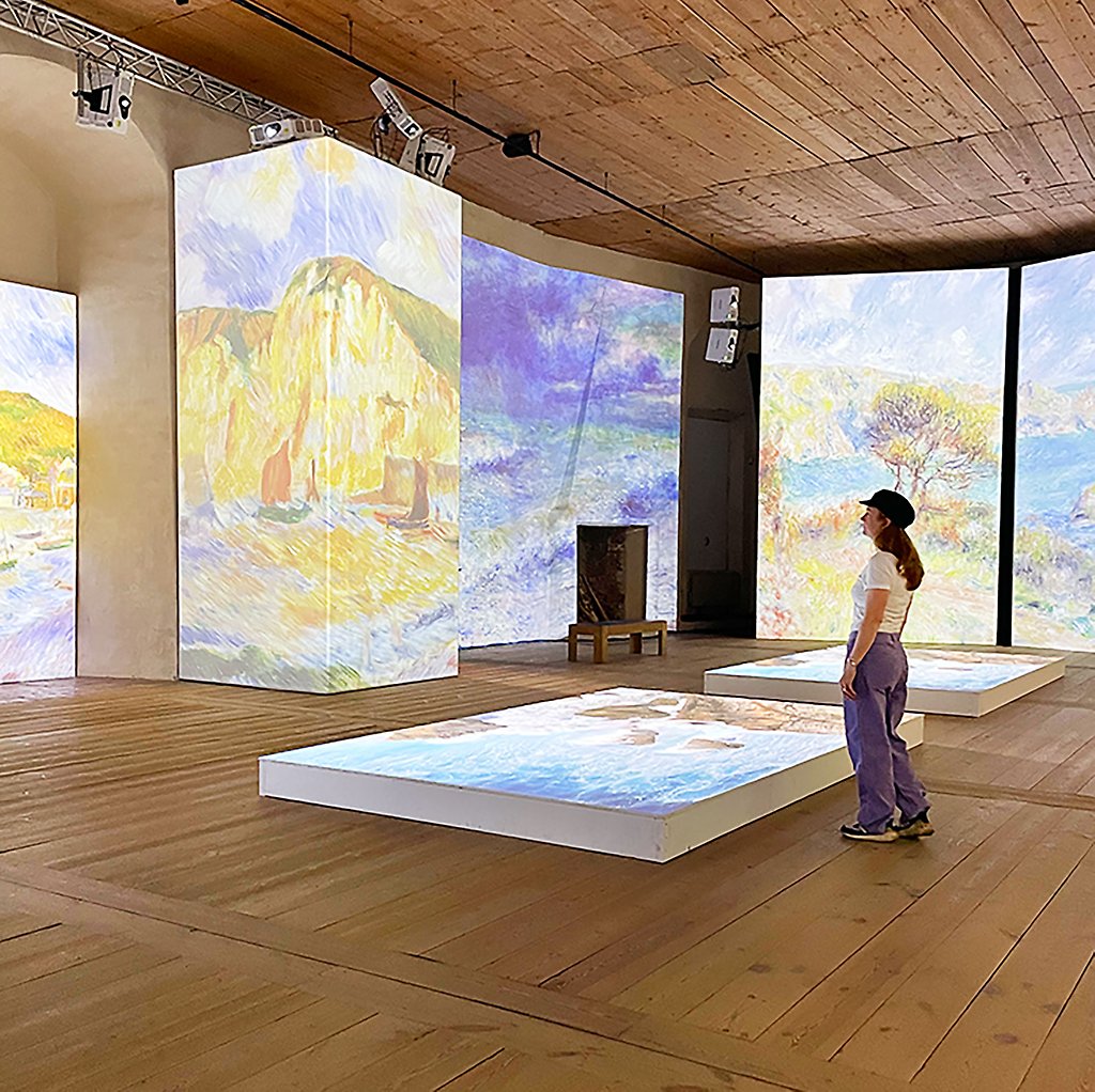 Sara Zetterström står i utställningen och tittar på skärmar med konst.