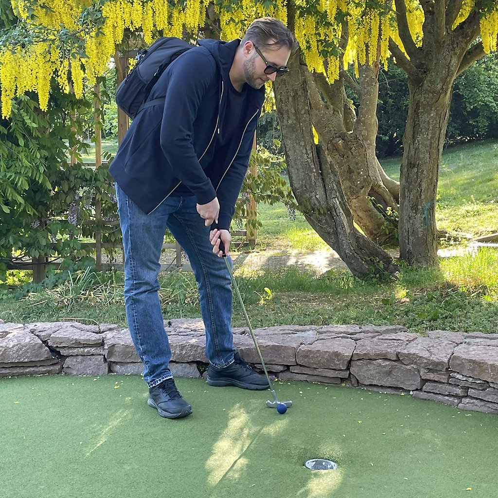 Alex står på banan och håller i en golfklubba
